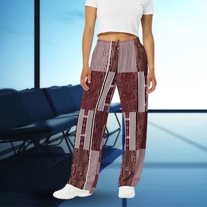 May include: Burgundy, brown, and white patchwork wide-leg trousers. The design incorporates vertical stripes, geometric shapes, and peace symbols. The trousers are made from a soft, flowing material, suitable for casual wear. The trousers have a high waist.