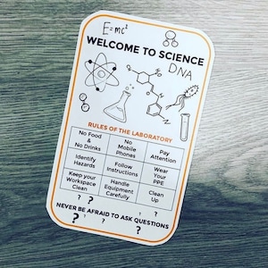 May include: A white sticker with an orange border that says "Welcome to Science" with a variety of science-related images and text. The text on the sticker includes "E=mc²", "DNA", "Rules of the Laboratory", and "Never be afraid to ask questions".