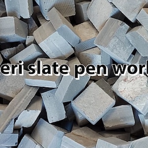 Op de afbeelding: Een stapel grijze leistenen kubussen. De afbeelding bevat de tekst "meri slate pen works" en "Black cubes". De kubussen zijn ruwweg rechthoekig en lijken uit steen gesneden te zijn.