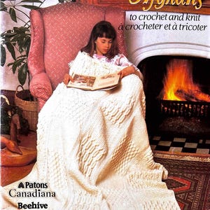 Può includere: Una persona è seduta in una poltrona rosa, avvolta in un afgano color crema strutturato. L'afgano presenta vari motivi a maglia. L'immagine è tratta da un libro di modelli vintage intitolato "Afghans to crochet and knit" di Patons.