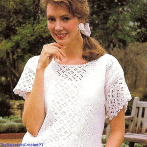 Puede incluir: Top blanco de ganchillo con un delicado patrón de encaje y mangas cortas. El top tiene un escote redondo y una silueta ligeramente ajustada.