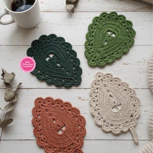 May include: Four leaf-shaped crochet coasters in dark green, light green, beige, and terracotta. Each coaster features a scalloped edge and a central cutout. A pink circular logo with the text Shop: TheSweetestCrochetPT is visible.