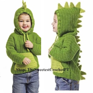 May include: Green crocheted dinosaur hoodie with a hood and a tail. The hoodie has a pocket on the front and a drawstring. Shop: The Sweetest CrochetPT.