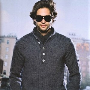 Puede incluir: Un suéter de punto gris oscuro con cuello abotonado y mangas largas. El suéter tiene un patrón de punto texturizado y un ajuste holgado.