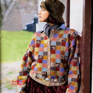 Może przedstawiać: Kobieta w wielokolorowym kardiganie w patchwork z brązowym filcowym kapeluszem i burgundową aksamitną spódnicą. Kardigan zapinany jest na guziki i ma pasek z srebrnymi akcentami.