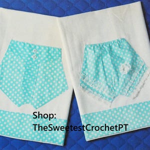 May include: Two white fabric panels with a blue and white polka dot trim. Each panel has a blue and white polka dot pocket with a white button detail. The text "Shop: TheSweetestCrochetPT" is printed on the bottom of the panels.