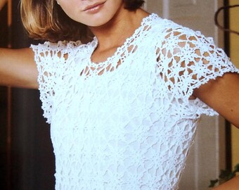 May include: A white crochet top featuring a floral design around the neckline and sleeves. The top has an open, delicate weave. The text "Shop: TheSweetestCrochetPT" is visible at the bottom of the image.