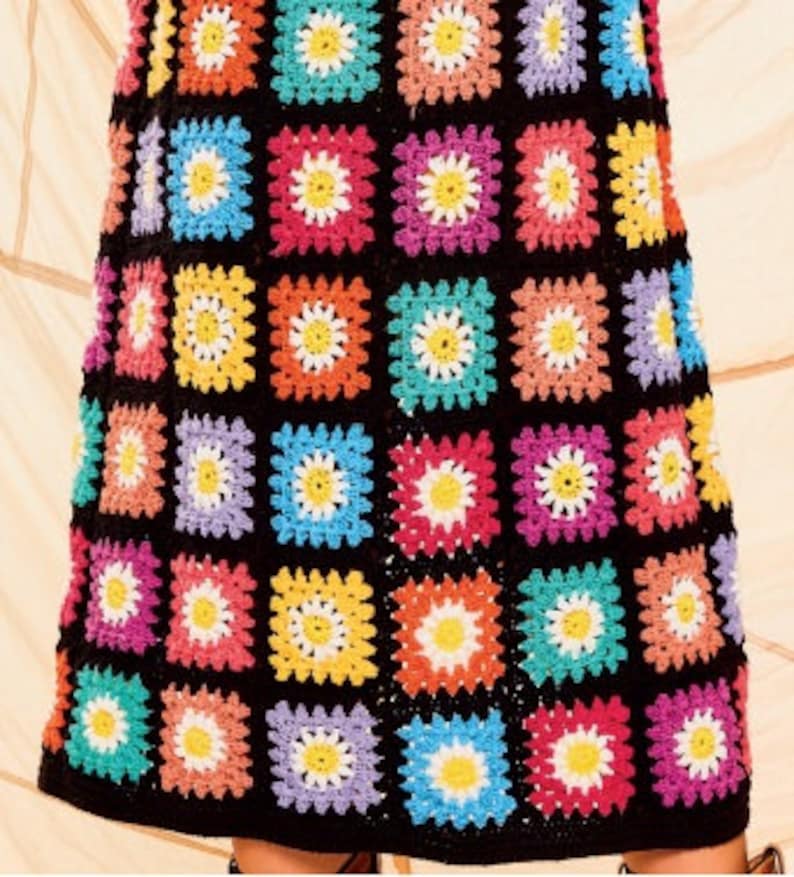 Pu&ograve; includere: Una gonna a uncinetto colorata con sfondo nero e un motivo a margherita. La gonna &egrave; composta da pi&ugrave; quadrati di diversi colori, tra cui rosa, blu, giallo, verde e viola.