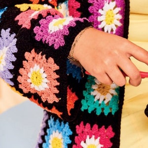 Pu&ograve; includere: Primo piano di un cardigan nero all'uncinetto con quadrati a forma di fiore colorati. Il cardigan ha maniche lunghe e una vestibilit&agrave; ampia.