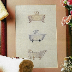 Puede incluir: Un diseño de punto de cruz enmarcado que presenta tres estilos diferentes de bañeras. Las bañeras están bordadas en hilo marrón, azul y blanco. El diseño está sobre un fondo beige.