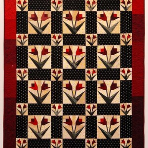 May include: A quilt with a black and white checkered pattern and red tulip designs. The quilt has a red border.