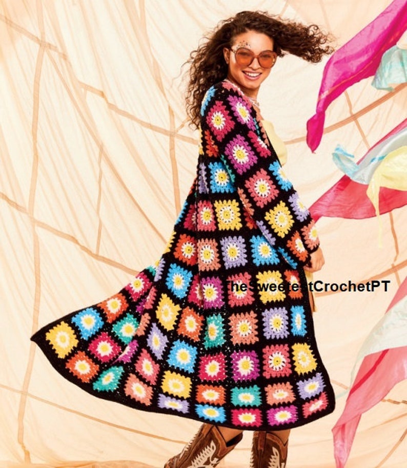 Pu&ograve; includere: Un lungo cardigan all'uncinetto colorato con sfondo nero e un motivo a margherita. Il cardigan &egrave; composto da quadrati di diversi colori, tra cui rosa, blu, verde, giallo e arancione. Il cardigan &egrave; indossato da una persona con i capelli ricci e occhiali da sole.