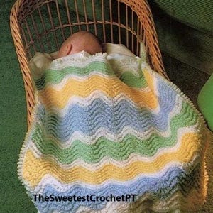 May include: A baby is sleeping in a wicker bassinet, covered with a crocheted baby blanket with a wavy stripe pattern in yellow, green, blue, and white.