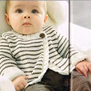 May include: A baby wearing a white and brown striped knitted cardigan with a brown button. The cardigan has a slightly ruffled hem.