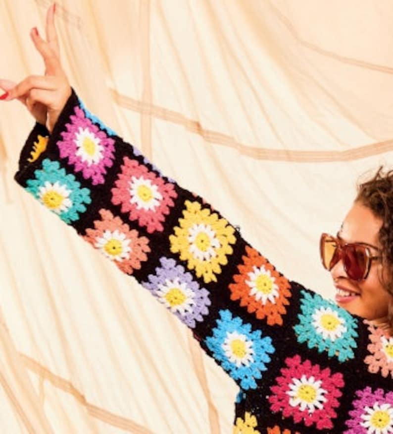 Pu&ograve; includere: Un top in crochet nero con quadrati colorati a forma di margherita. Il top ha maniche lunghe e una vestibilit&agrave; comoda.