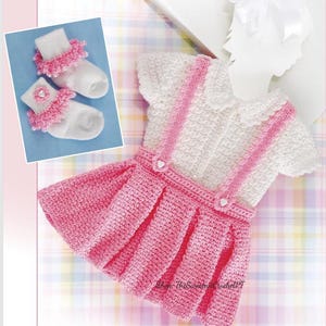 May include: A pink and white crocheted baby dress with a white crocheted collar and pink straps. The dress has a skirt with pleats and is decorated with white buttons.