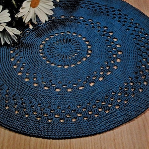 May include: A blue crocheted doily with a circular design and a scalloped edge.