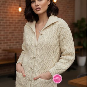 Può includere: Cardigan color crema a maglia a trecce con collo e chiusura a bottoni. Il maglione presenta due tasche frontali e intricati motivi intrecciati. L'immagine include il testo "Shop: TheSweetest CrochetPT".