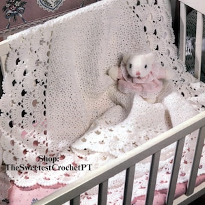 May include: A white crochet baby blanket with a scalloped edge and a matching white stuffed animal in a crib. The crib has a pink floral patterned sheet. The text "Shop: TheSweetestCrochetPT" is visible.