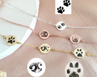 May include: Three silver, gold, and rose gold necklaces with paw print charms. Each necklace features a different paw print design.