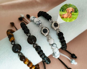 Peut inclure: Quatre bracelets avec des perles noires, brunes, blanches et noires. Chaque bracelet a un charme argenté avec un motif d'œil noir. Un bracelet a une petite photo d'un chien dans l'œil.