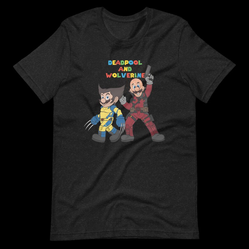 May include: A dark heather grey t-shirt with a graphic print of Deadpool and Wolverine in a cartoon style. The text "DEADPOOL AND WOLVERINE" is printed in rainbow colors above the characters.