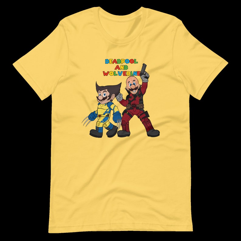 May include: Yellow t-shirt with a graphic of Deadpool and Wolverine in a cartoon style. The text "DEADPOOL AND WOLVERINE" is printed in colorful letters above the characters.