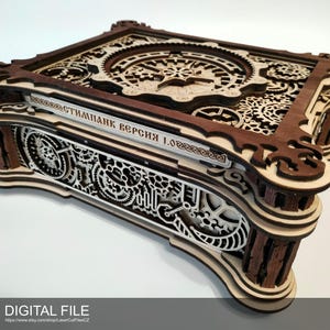 May include: A wooden box with intricate laser-cut designs, featuring gears and clockwork elements. The box is constructed from layers of light and dark brown wood, with detailed patterns on the top and sides. Text is visible on the side of the box.
