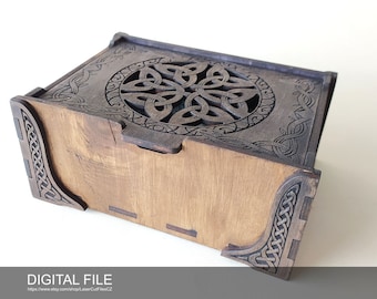 Puede incluir: Una caja de madera con un diseño de nudo celta tallado en la tapa. La caja está hecha de madera marrón claro y tiene una mancha marrón oscura. La caja está cerrada y la tapa está ligeramente entreabierta.