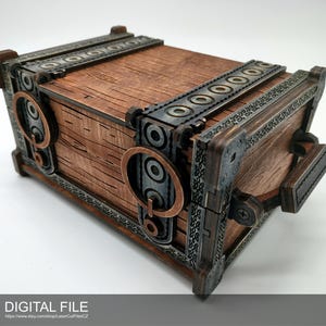Puede incluir: Una caja de madera con detalles metálicos y un pestillo. La caja está decorada con diseños intrincados y tiene un acabado de madera desgastada.