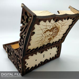 Peut inclure: Une tour à dés en bois avec un design complexe et une tête de loup gravée sur le couvercle. La tour est ouverte et le couvercle est relevé.