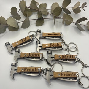 Könnte beinhalten: Sechs personalisierte Hammer-Schlüsselanhänger mit Holzgriffen. Die Schlüsselanhänger sind mit den Namen TJ, Josh, John, Matt, Frank und Francis graviert.