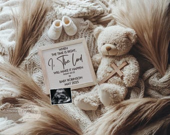 Pode incluir: Um cartaz branco com uma inscrição preta que diz "Quando o tempo estiver certo, eu, o Senhor, farei acontecer Isaías 60:22" com um coração e o texto "Baby Robinson Maio 2025". Um urso de peluche com uma cruz de madeira está sentado em um cobertor bege com um cobertor de malha branco e bege.