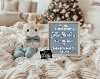 May include: A knitted reindeer toy with a blue bow tie and matching blue baby booties sits on a cream-coloured blanket. A letter board announces "We are excited to say a Little Brother is on the way!" with the baby's name and due date.
