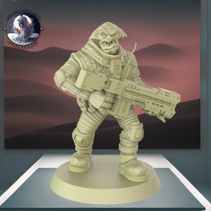 Könnte beinhalten: Hellbeige Miniaturfigur eines humanoiden außerirdischen Soldaten, der ein großes Gewehr hält. Die Figur trägt einen detaillierten Raumanzug mit Knieschonern und Stiefeln. Die Figur steht auf einem runden Sockel. Der Hintergrund zeigt eine Wüstenlandschaft.