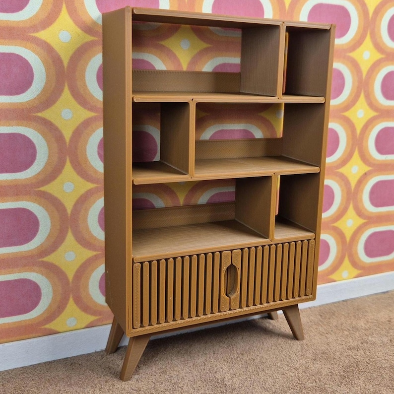 May include: A mid-century modern style wooden bookcase with multiple shelves and a lower cabinet. The bookcase is a warm brown color, with a vertical slatted design on the cabinet door. It stands on angled legs.