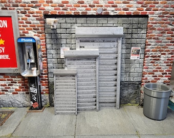 Puede incluir: Tres puertas enrollables de metal gris con un aspecto desgastado. Las puertas son de diferentes tamaños y están cerradas. Las puertas están frente a una pared de ladrillo.
