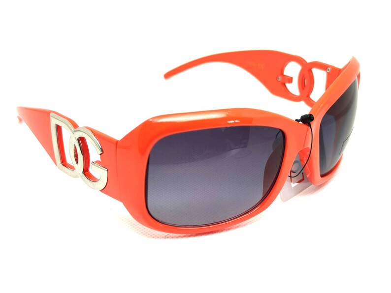 May include: Orange sunglasses with a silver logo on the side. The logo is the letters "DG" in a stylized font.