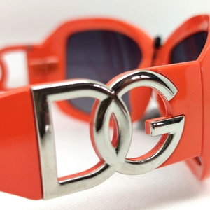 May include: Orange sunglasses with a silver DG logo on the front.