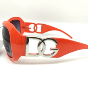 May include: Orange sunglasses with a silver DG logo on the frame.