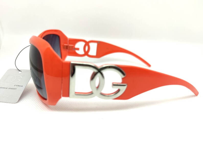 May include: Orange sunglasses with a silver DG logo on the frame.