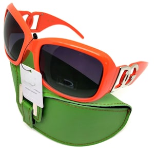 May include: Orange sunglasses with a silver logo on the side, in a green case.