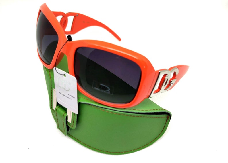 May include: Orange sunglasses with a silver logo on the side, in a green case.