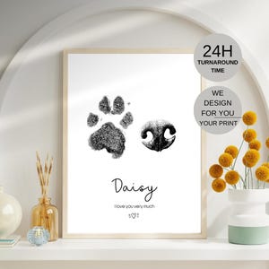 May include: A framed print featuring a black paw print and a dog's nose print. The name "Daisy" is written below, along with the phrase "I love you very much." Additional text includes "24H Turnaround Time" and "We Design For You Your Print."