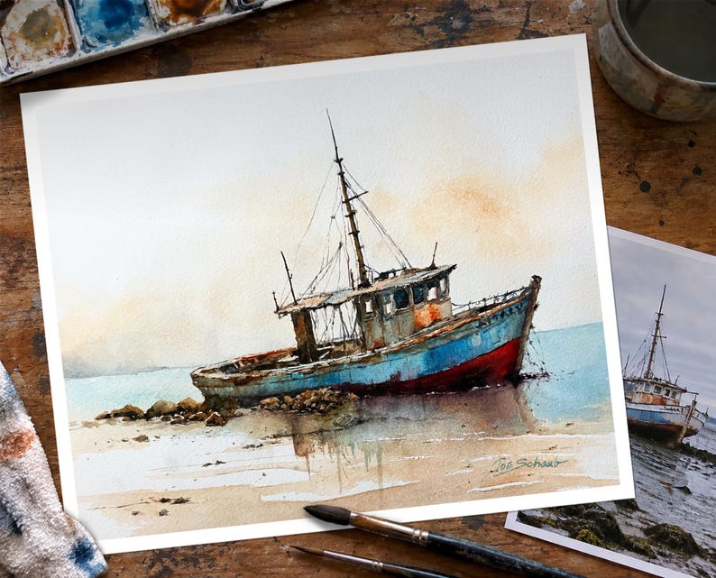 May include: A watercolor painting of a weathered fishing boat resting on a sandy shore. The vessel features a blue hull with a red lower section, a tall mast, and a cabin. The artist's signature, Joe Schaub, is visible in the bottom right corner.
