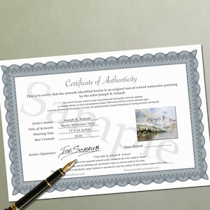 May include: A Certificate of Authenticity for a watercolor painting titled Rocky Mountain Vista by Joseph R. Schaub, dated 2026, with a painting size of 11 x 14 inches, featuring a mountain landscape image and a black fountain pen resting on the document.