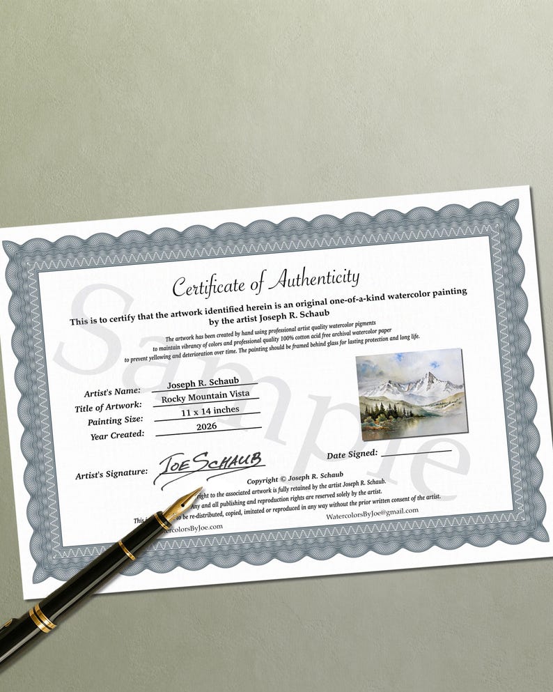 May include: A Certificate of Authenticity for a watercolor painting titled Rocky Mountain Vista by Joseph R. Schaub, dated 2026, with a painting size of 11 x 14 inches, featuring a mountain landscape image and a black fountain pen resting on the document.
