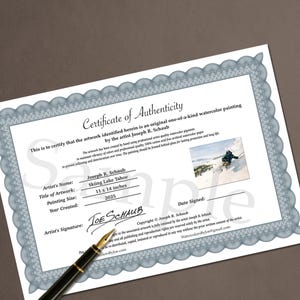May include: A certificate of authenticity for a watercolor painting, featuring a blue and white border design. The certificate includes the artist's name, artwork title "Skiing Lake Tahoe", painting size 11 x 14 inches, and year created 2025. A black pen rests on the certificate.