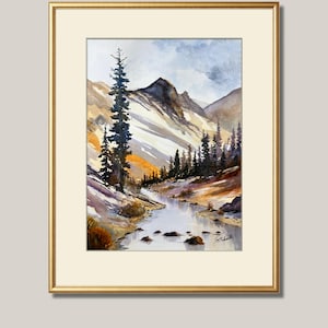 May include: Watercolor painting of a mountain landscape with a river. The artwork features a gold frame and a cream-colored mat. The scene includes snow-capped mountains, evergreen trees, and a flowing river. The sky is a mix of blue and gray.