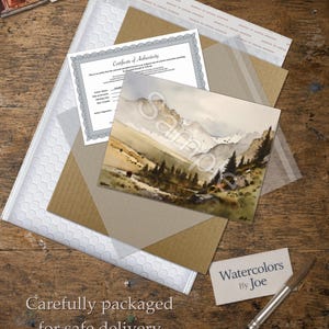 May include: A watercolor landscape painting of a mountain range with pine trees and a small stream, accompanied by a Certificate of Authenticity, a white bubble mailer, a brown cardboard backing, and a business card labeled Watercolors By Joe.